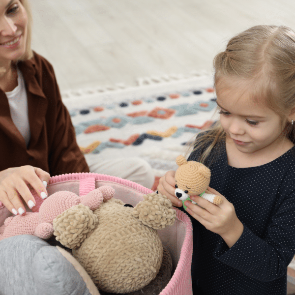 Petite fille qui range ses jouets devant sa maman