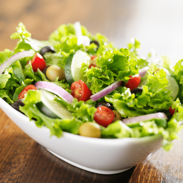 coupelle avec une salade de printemps composée de salade verte, de tomates, d'olive et d'oeufs